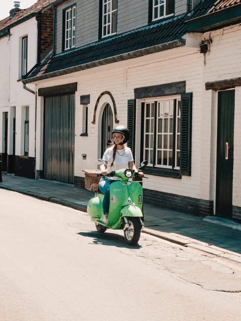 Frau fährt Vespa in Brügge