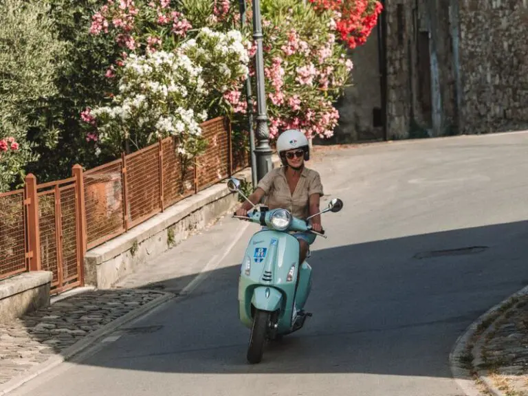 Blaue Vespa, die durch die Toskana fährt.