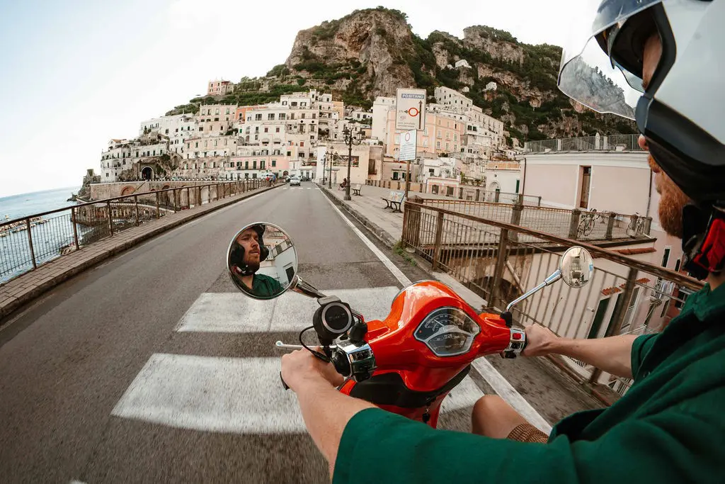 Mann auf einer roten Vespa, der durch eine Stadt an der Amalfiküste fährt
