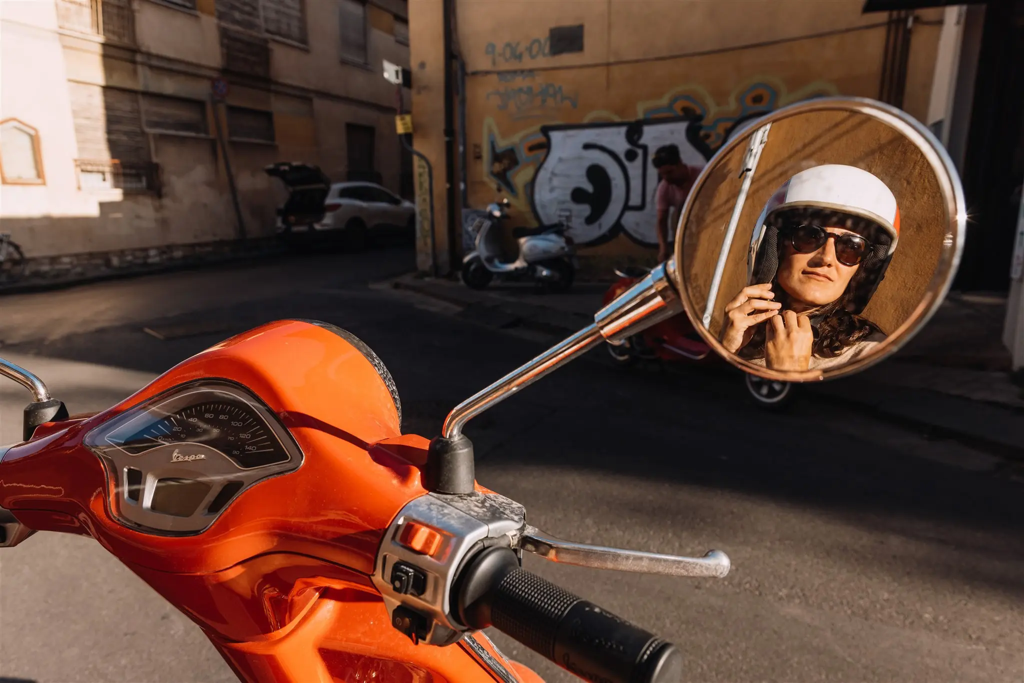 woman in helmet reflected in scooter mirror in Tuscany