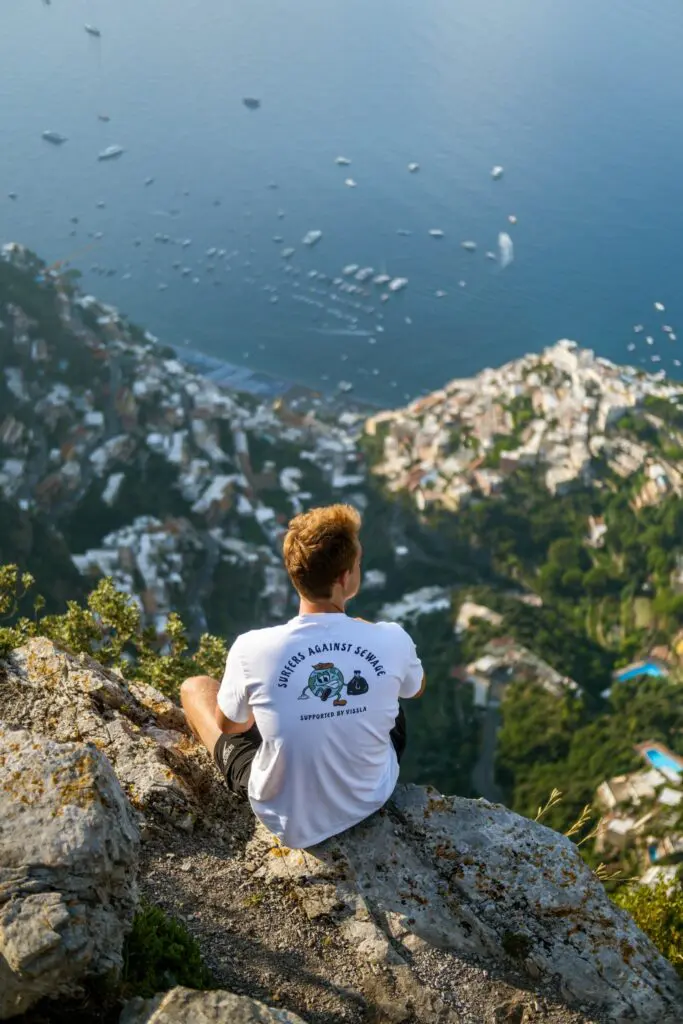 Mann auf einer Klippe mit Blick auf Positano an der Amalfiküste