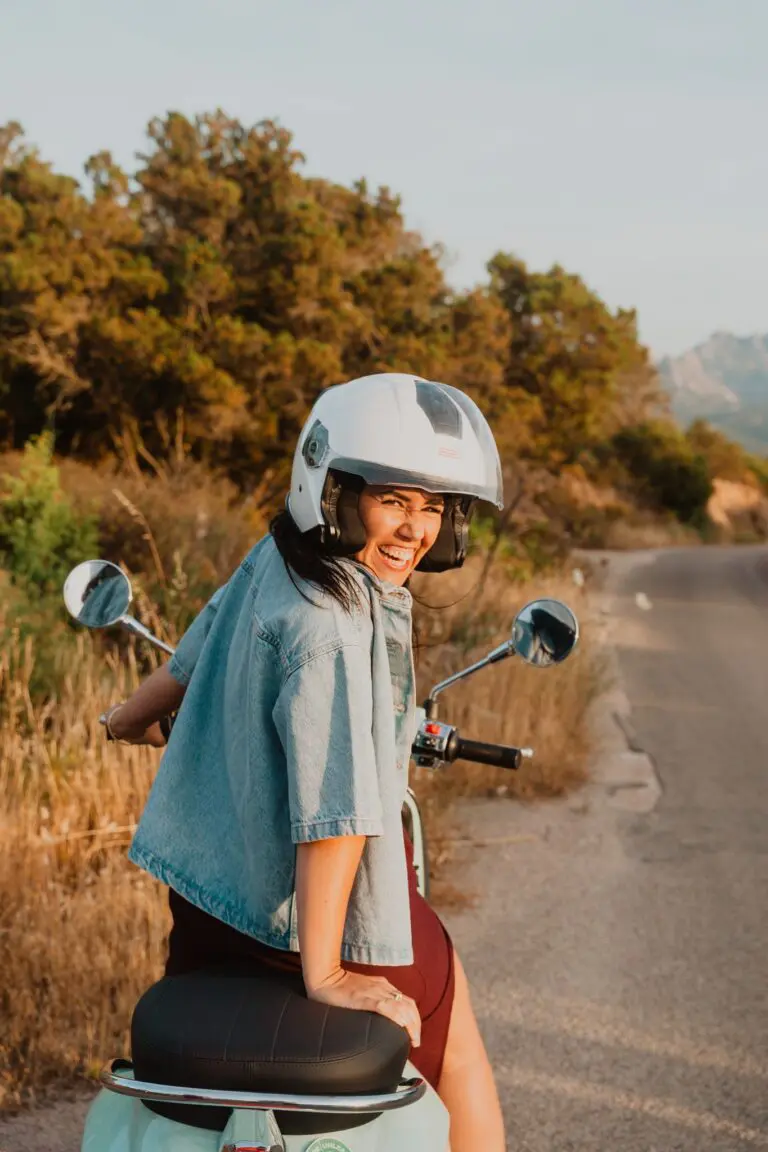Frau mit Helm auf einem Motorroller auf einer Straße in Sardinien