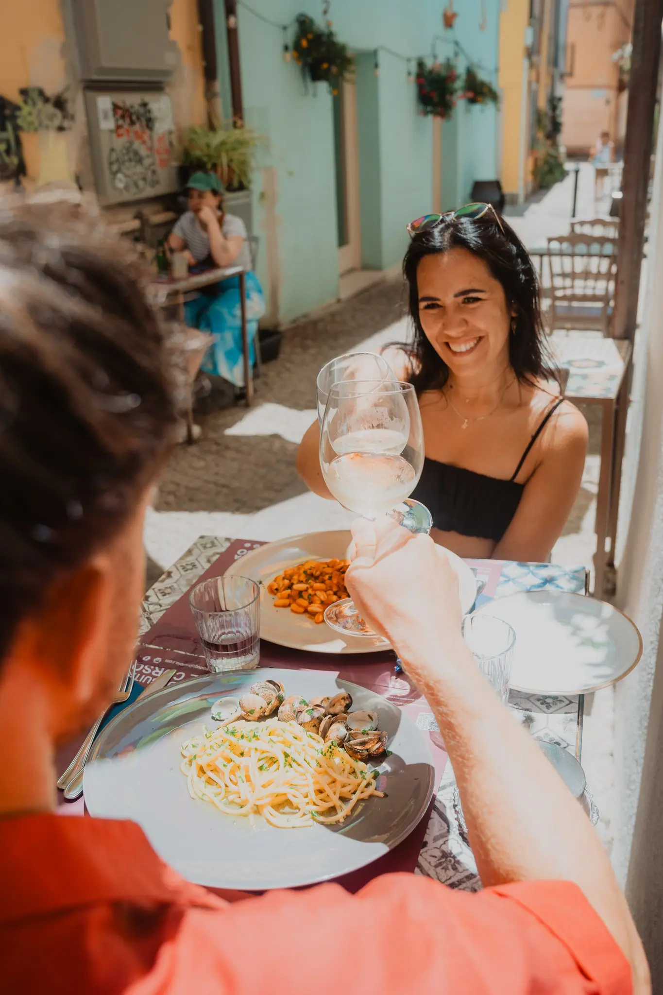 Paar, das sich in einem Restaurant im Freien auf Sardinien mit Wein zuprostet