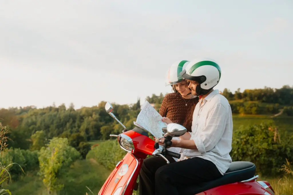 Paar auf einer roten Vespa, das in Venetien auf eine Karte schaut