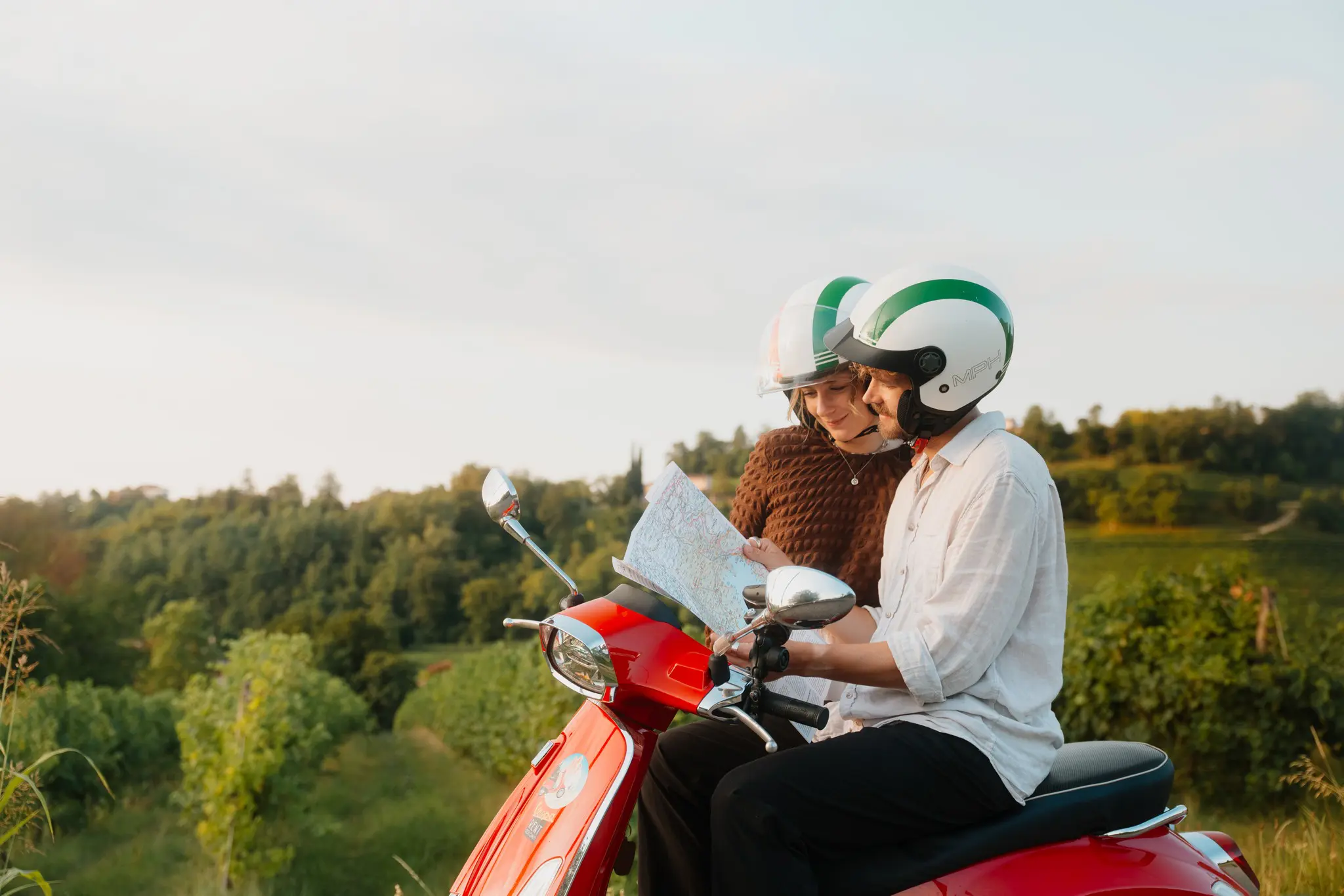 Paar auf einer roten Vespa, das in Venetien auf eine Karte schaut
