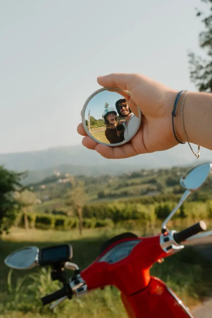 Paar beim Spiegel-Selfie auf einem Motorroller in der Landschaft Venetiens