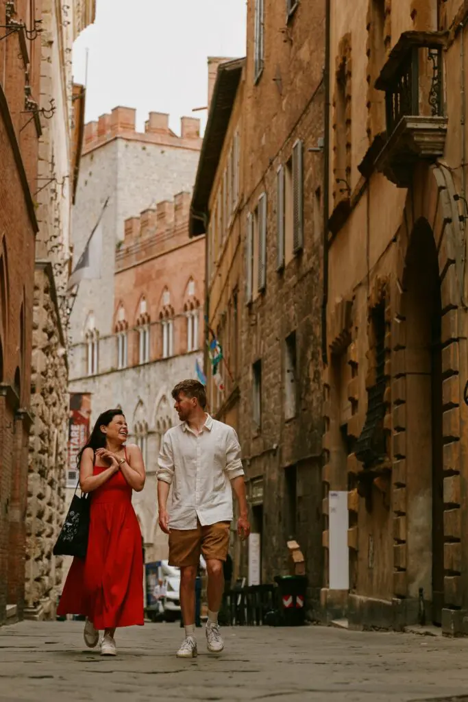 Paar, das durch eine enge Straße in Siena geht und lacht