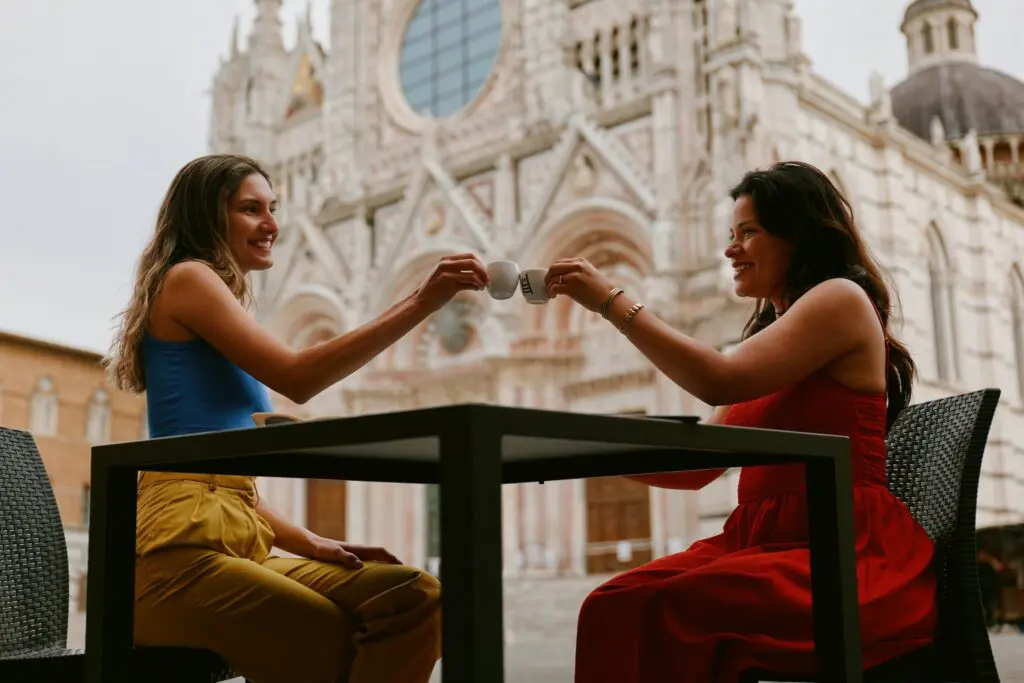 zwei Frauen, die vor dem Dom von Siena mit Espresso anstoßen