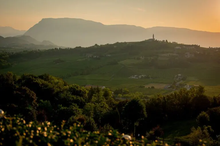 Weinberge und ein Dorf mit Glockenturm bei Sonnenuntergang in Venetien
