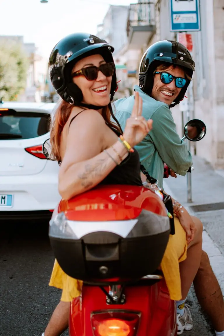 Paar auf einem roten Motorroller lächelt in Apulien, Italien