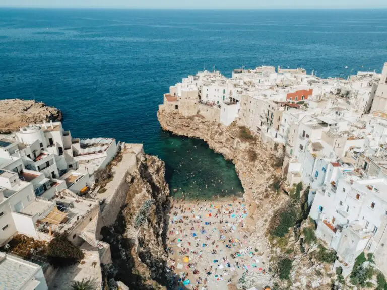 Drohnenaufnahme vom Strand von Polignano a Mare und der weißen Stadt an der Steilküste