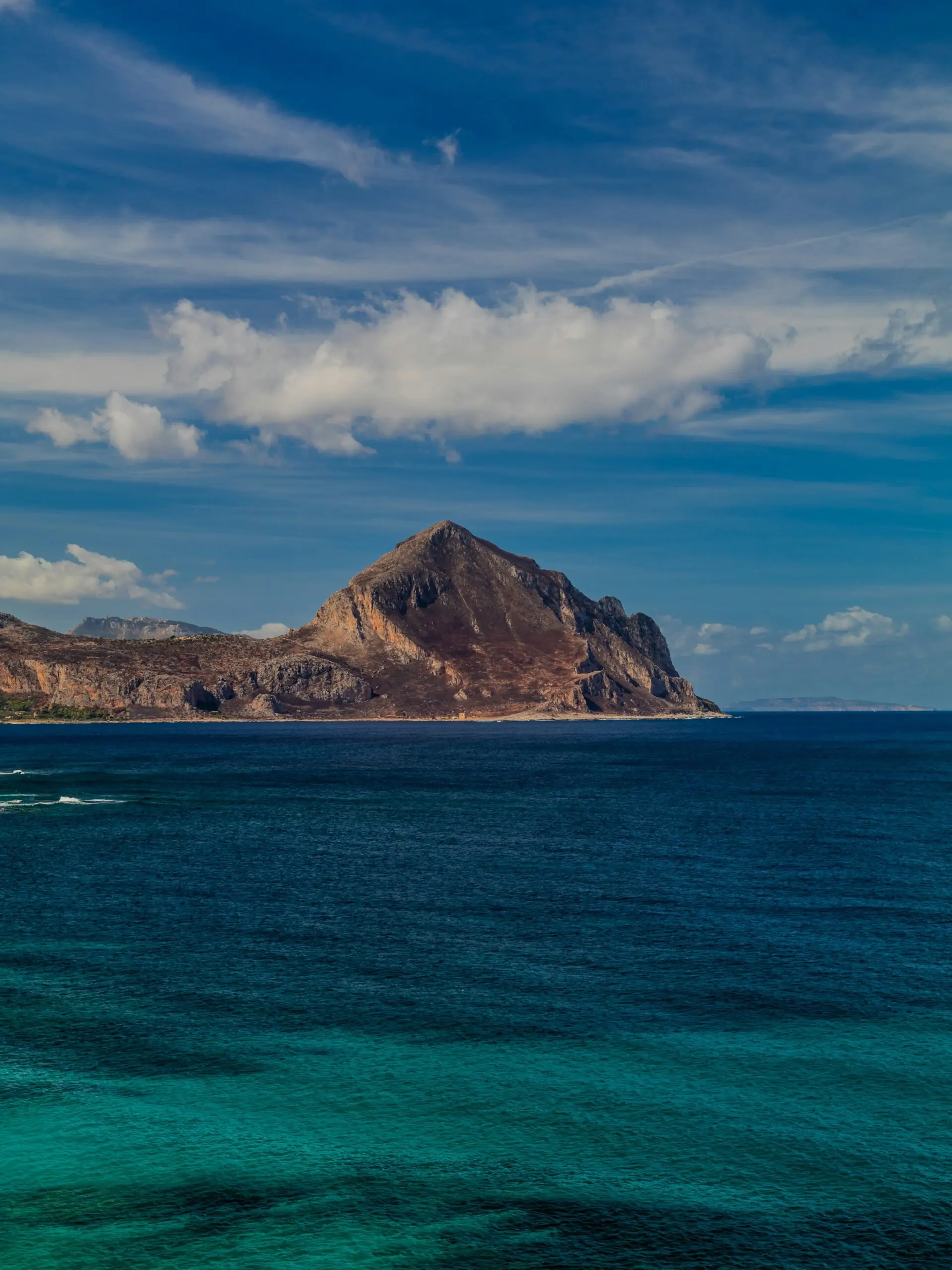 Mountainous coastline meets turquoise ocean under blue sky