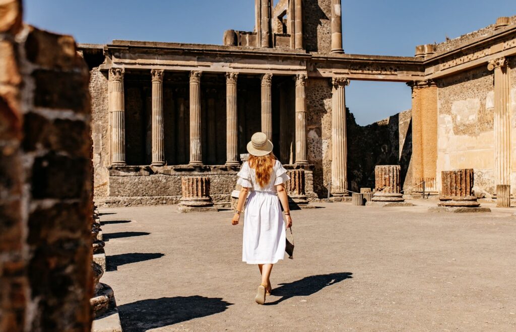 woman in white dress walking through ancient ruins in Pompeii