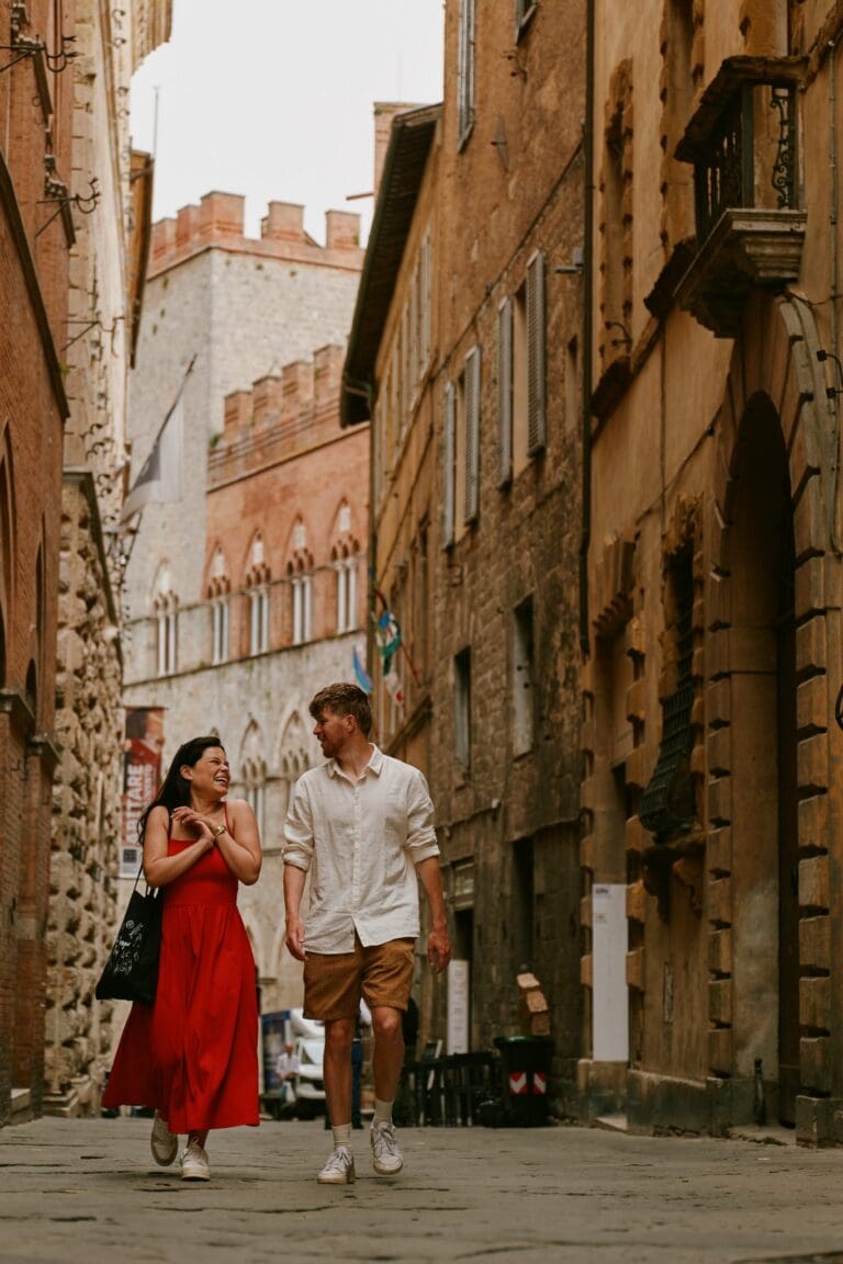 Paar, das durch eine enge Straße in Siena geht und lacht