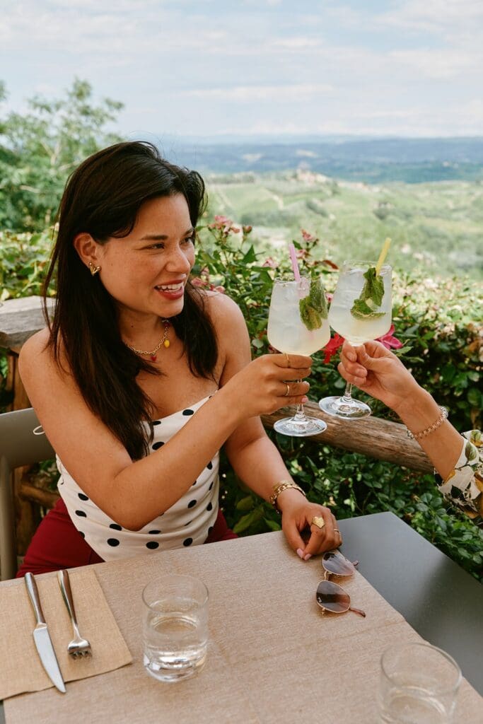 zwei Frauen, die auf einer Terrasse mit Blick über die Toskana anstoßen
